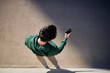 © baranq - Overhead picture of a man using smartphone on city street wearing hooded sports sweatshirt