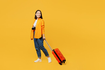 young woman wear summer casual clothes walk go with suitcase bag look aside isolated on plain yellow