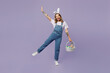 Full body smiling fun young woman wearing casual clothes bunny rabbit ears holding wicker basket colorful eggs raising hand up isolated on plain pastel purple background studio. Happy Easter concept.