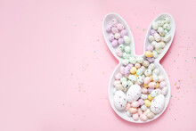 
Spring Easter Layout. Bunny Plate With Easter Painted Eggs And Confetti On A Pastel Pink Background. Top View. Copy Space. Flat Lay. Place For Text.