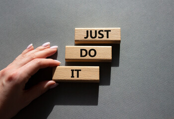 Wall Mural - Just do it symbol. Wooden blocks with words Just do it. Beautiful grey background. Businessman hand. Business and Just do it concept. Copy space.