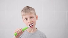 Cute Boy Brushing Teeth With An Electric Brush And Then Funny Shows Their Purity. Fun Lifestyle. Children Smile. Hygiene, Health Care, Dental. Play Dentist Game, Daily Morning Procedures