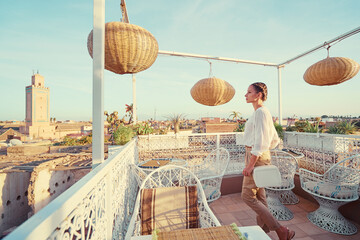 Wall Mural - Young traveling woman enjoying the view of Marakech on roof top terrace.