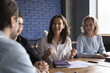 © fizkes - Cheerful young office employee girl meeting with colleagues at office conference table, sharing idea, smiling, laughing, having fun. Diverse coworkers brainstorming, discussing sales