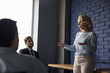© fizkes - Serious elder mature business coach woman presenting seminar to group, speaking before office team. Leader talking to employees on brainstorming meeting, explaining task