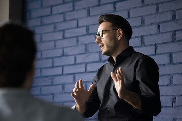 Wall Mural - Smart engaged handsome business leader man in glasses presenting project, idea for startup before group, speaking on office corporate meeting, using hand gestures