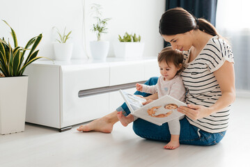 mother and daughter watch photobook from discharge of newborn baby.family tradition of printing photos and looking at them with children and remembering.photographer and designer