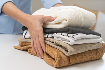 Feel softness, asian young woman, female hand holding pile clothing from table, stack folding clean clothes after washing, laundry and dry. Household working at home. Laundry and maid concept.