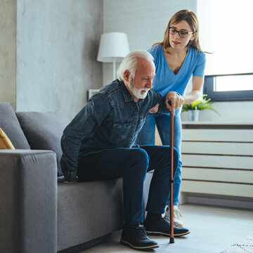 doctor or nurse caregiver helping senior man with a walking cane stick at home or nursing home. cari