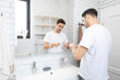 © Vitaliy - Handsome man brushing teeth in the bathroom. Morning routine concept