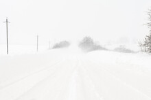A Heavy Snowstorm Covers The Road. Large Snowdrifts On The Sides Of A Rural Road. Poor Visibility During A Snow Cyclone