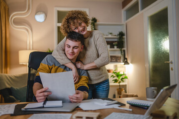 Young man male student teenager and his mother celebrate scholarship read mail letter happy exited smiling reading entry test results success celebrating achievement concept copy space real people