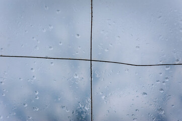 Home-made construction, a canopy, a greenhouse made of transparent cloth against the sky. Raindrops on a wet surface. Texture, abstraction, close-up photography.