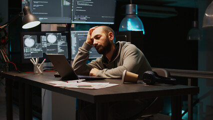 Tired IT engineer sleeping and trying to work on programming, falling asleep at app developing job. Young adult working with new interface to create database server system. Handheld shot.