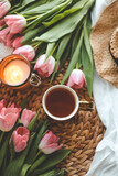 Fototapeta Tulipany - Beautiful spring composition, a cup of tea, tulips, a candle and a hat