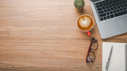 Wall Mural - Wooden desk workplace with laptop computer, notebook. eyeglass, pen and cup of cofeee, Top view flat lay with copy space.