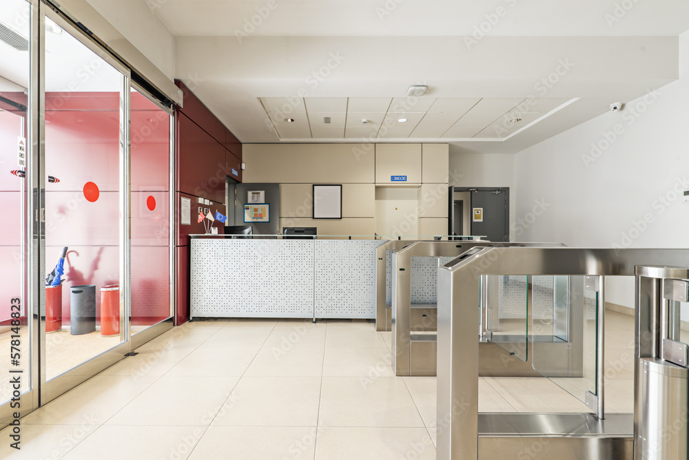 Entrance to an office building with access control with glass doors with key cards, empty reception desk and automatic glass doors