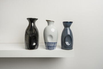 Small decorative porcelain vases of various colors on a white wooden shelf