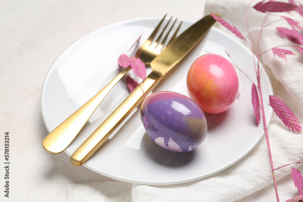 Table setting with Easter eggs, cutlery and plant branch on white background