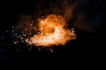 Wall Mural - Split debris of stone exploding with orange dust against black background.