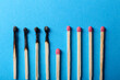 Burnt and whole matches on light blue background, closeup. Stop destruction by breaking chain reaction concept
