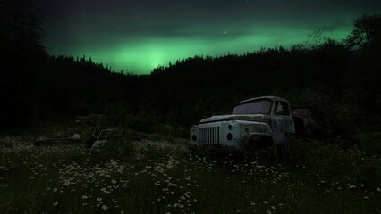 Wall Mural - Northern Lights (Aurora Borealis) above the old abandoned truck in the flowery field at night. Time Lapse