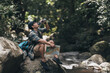 © Charnchai saeheng - The trekker was looking at the map to find the hiking trails at the stream and drink water in the forest. hiking and adventure concept..