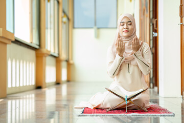 The image of an Asian Muslim woman in the Islamic religion in hijab in cream color. She was praying in a beautiful mosque out of respect for God.