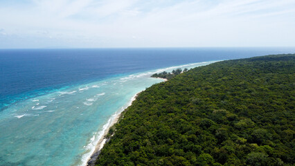 Wall Mural - Aerial view of vast tree covered tropical island landscape of Jaco Islan in Timor Leste, protected by coral reef marine ecosystem in Coral Triangle in Southeast Asia 