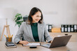 © Nuttapong punna - Beautiful Asian woman using laptop and tablet while sitting at her working place. Concentrated at work..