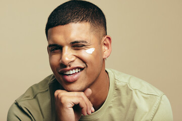 Wall Mural - Fun skincare routine: Handsome young man smiles with beauty cream on his face