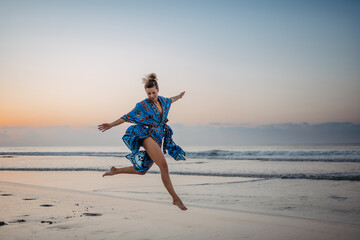 Wall Mural - Young woman enjoying time at sea, jumping.