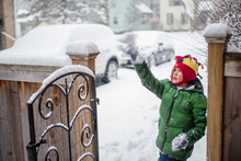 Portrait Of A Small Boy By A Gate Playing In Falling Snow