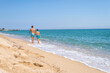 © Cavan Images - Rear view of father and son walking along the beach in a sunny day
