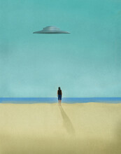 Person Looking At Flying Saucer Hovering Over Sandy Beach