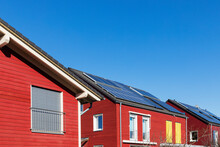 Germany, North Rhine Westphalia, Cologne, Row Of Red-painted Wooden Houses With Solar Roof Panels