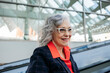 Happy businesswoman wearing eyeglasses on escalator at station