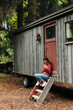 © Westend61 - Woman using smart phone sitting in front of cabin
