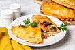 Baked meat turnovers or pies, or empanadas, or cornish pasty with filling, beef, carrot, and potato, white plate.