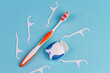 Toothbrush with dental floss picks and thread. Top view blue background.