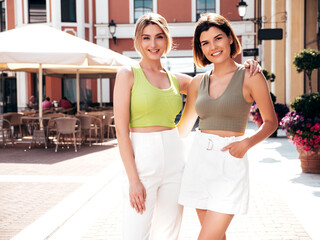 Poster - Two young beautiful smiling hipster female in trendy summer t-shirt and shorts clothes. Sexy carefree women posing on street background. Positive models having fun, hugging