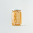 Honeycomb and golden honey in glass jar on isolated pastel white background. The idea of alternative therapy or eating raw, healthy sweet food. Minimal creative concept of natural beekeeping products.