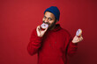 © Drobot Dean - Young indian man eating sweet donuts isolated over red background