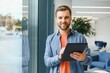 © Serhii - Portrait of young businessman with tablet standing in an office, working.