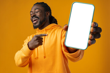 Smiling african man pointing at cellphone with blank screen with copy space