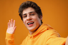 Young Handsome Man Wearing Casual Hoodie Waiving Saying Hello On Yellow Background