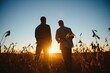 © Serhii - Two farmers in a field examining soy crop at sunset
