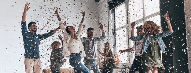 Wall Mural - Happy young people dancing while having a party with confetti flying around them