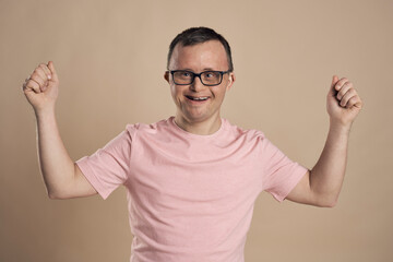 Man with down syndrome celebrating success at nude background