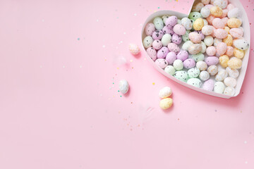 Wall Mural - heart shaped box filled with easter eggs on a pastel pink background with confetti. top view. copy space. flat lay